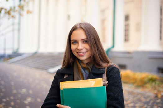 Portrait of a smiling student girl on the background of university building