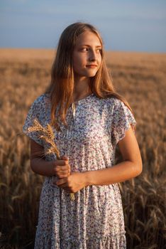 Portrait of attractive girl with bouquet of ripe wheat ears in hands