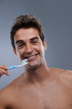 Hes committed to dental hygiene. Studio portrait of a bare-chested young man about to brush his teeth.
