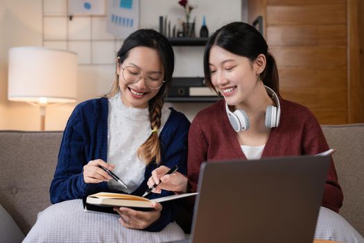 Two asian students learning together online with a laptop and tutor together at home