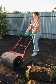Woman laying sod for new garden lawn - turf laying concept