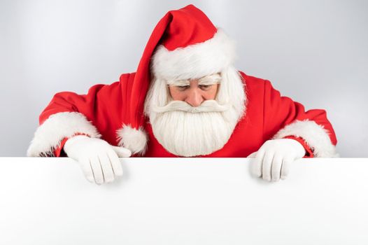 Santa Claus peeks out from behind an ad on a white background. Merry Christmas.