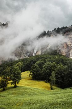Lauterbrunnen valley, Switzerland. Swiss Alps. Cozy small village in foggy mountains. Clouds and green meadows