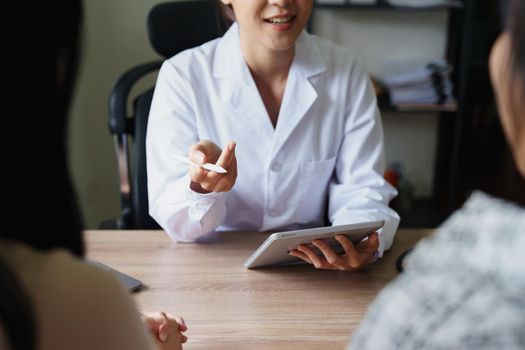 Portrait of a doctor advising clients on health issues holding a tablet to work and talking to patients who come to treatment