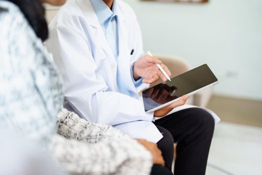 Portrait of a doctor advising clients on health issues holding a tablet to work and talking to patients who come to treatment