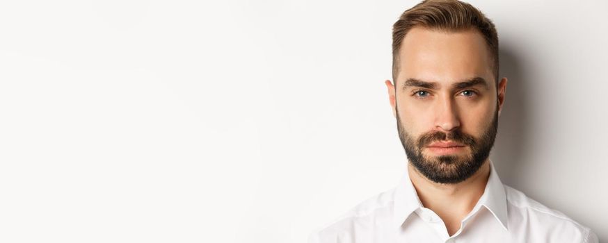 Emotions and people concept. Headshot of serious-looking handsome man with beard, looking confident and determined, white background