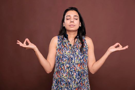 Serene indian woman meditating, showing om sign with fingers