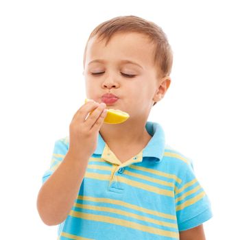 Instilling good eating habits. a cute young boy eating an orange slice isolated on white.