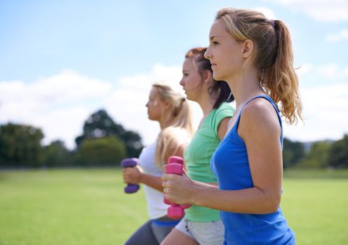 Sunshine and exercise. a group of young women exercising outdoors.