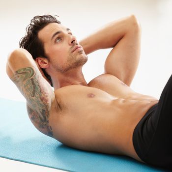 Getting a six pack starts here. A handsome young man doing crunches without a shirt.