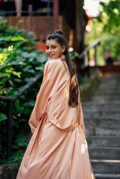 Young smiling woman on walking in the park wearing robe