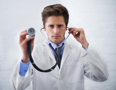 Examination time. a serious-looking doctor holding up the end of a stethoscope toward the camera.