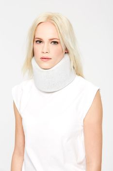 Getting better by the day. A beautiful young woman in a neck brace against a white background.
