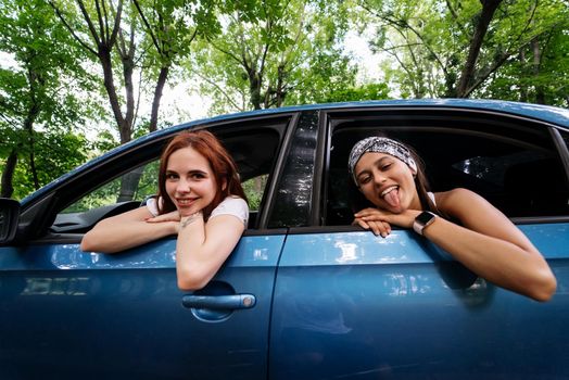 Two girlfriends fool around and laughing together in a car