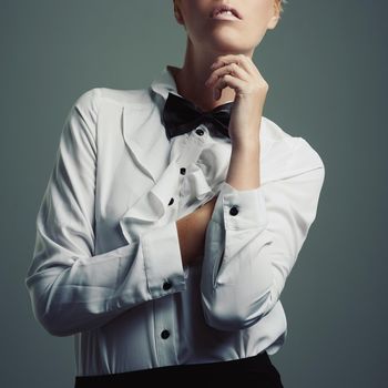 Simplicity is the ultimate sophistication. Studio shot of a young woman wearing a shirt and bow tie against a gray background.