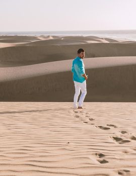 Young men walking at the beach of Maspalomas Gran Canaria Spain, men at the sand dunes desert