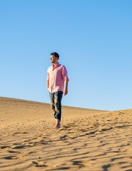Young men walking at the beach of Maspalomas Gran Canaria Spain, men at the sand dunes desert