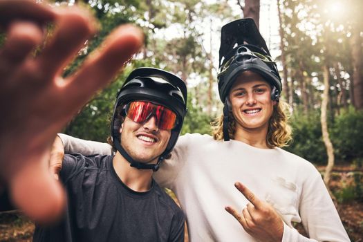Forest, cycling and friends take a selfie in nature on an outdoor bicycle adventure in the woods in summer. Sports, bikers and happy men in a picture for fun biking memories on holiday vacation