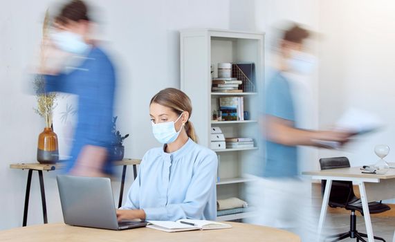 Business woman, busy office and covid compliance while on laptop and blur of people around her. Employees in the office during coronavirus wearing face mask and working in company after lockdown