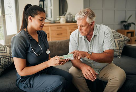 Nurse, senior man and home care or consultation for healthcare and medicine prescription with a caregiver reading on medication box. Female medical worker talking to a old male sitting on a sofa