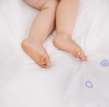 The picture of innocence. A cropped image of a babys legs lying on a bed.