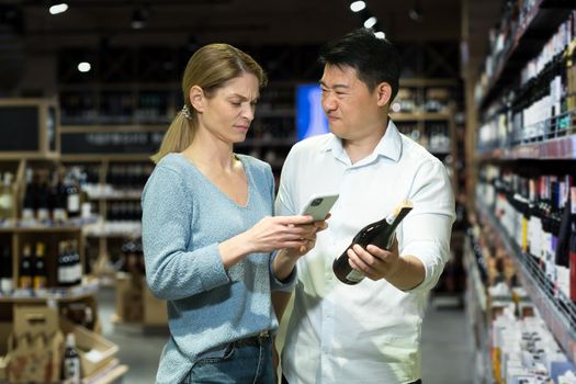 Dissatisfied international couple buying wine. They are holding a bottle and a phone