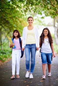 Shes a caring educator. A teacher walking with her two students to school.