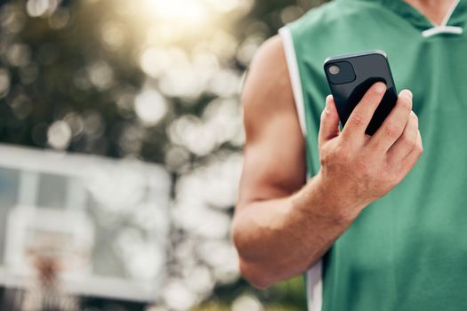 Man, hands and phone in sports communication and social media for basketball in the nature outdoors. Muscular male in sport fitness, exercise and game time check, message or text on mobile smartphone.