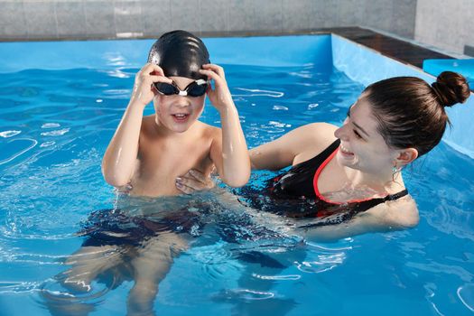 Boy learning to swim and dive in pool with teacher