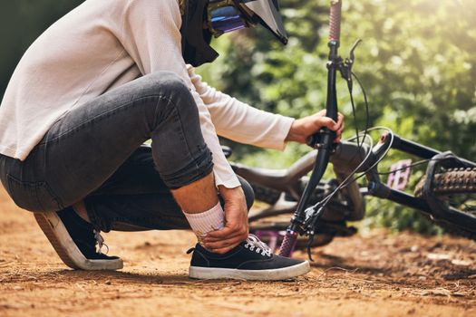 Sports bicycle and man with ankle injury on nature cycling trail in accident from bad decision. Cyclist athlete pain, inflammation and joint problem from dangerous wheel stunt movement.