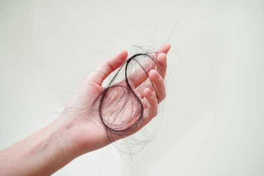 Asian woman have problem with long hair loss attach in her hand.