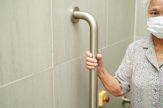Asian woman patient use toilet support rail in bathroom, handrail safety grab bar, security in nursing hospital.