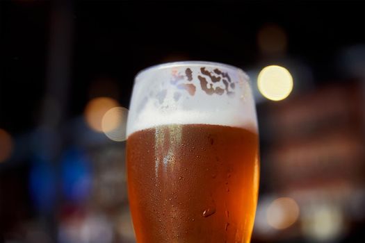 Glass of beer on a table in a bar on blurred bokeh background
