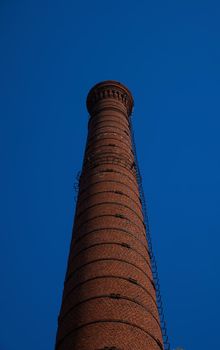 tall chimney old red bricks in an old factory. smoke stack An old brick chimney against a blue sky