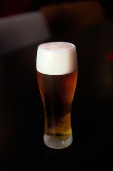 Fresh cold beer, glass of beer on a table in a bar on blurred bokeh background