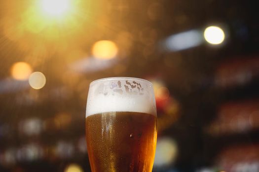 Glass of beer on a table in a bar on blurred bokeh background