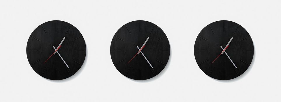 Stylish black round clock on a white wall. Time on the wall as an element of the interior. Simple modern round clock on white wall