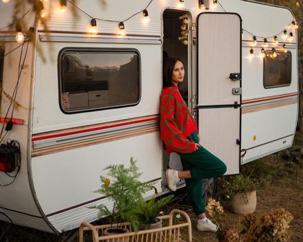 Caucasian woman in oversized red knitted jumper travels in motorhome in autumn.