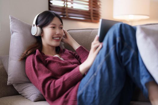 Attractive smiling young woman using tablet and listen music on sofa at home. lifestyle concept