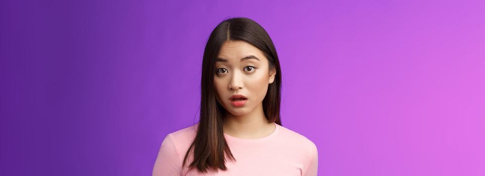 Close-up confused shocked cute young silly asian girl hear strange accusations open mouth gasping stunned, look speechless and puzzled, did not expect such behaviour, purple background