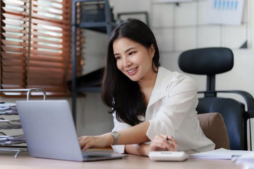 Asian business woman freelancer is working her job on a laptop. Doing accounting analysis report real estate investment data, Financial and tax systems concept