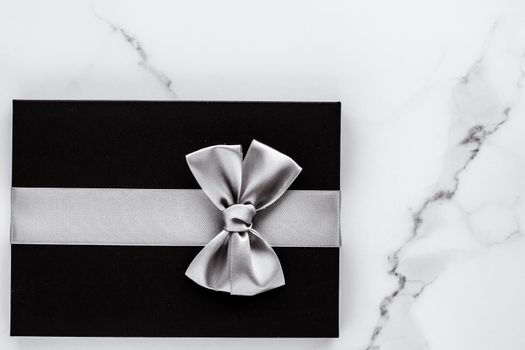 Luxury holiday gifts with silver silk ribbon and bow on marble background