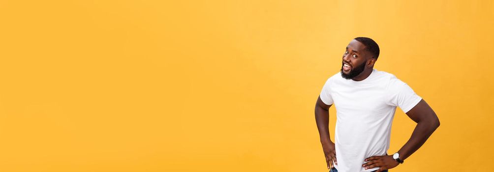 Portrait of handsome young african guy smiling in white t-shirt on yellow background
