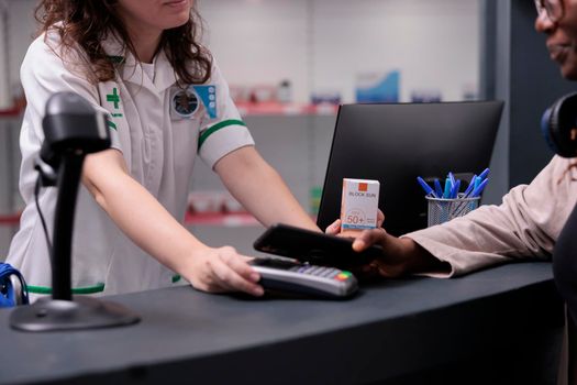 Close up of customer paying pharmaceutical shopping with modern phone