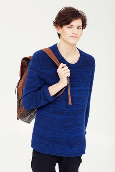 Looking good for college. A confident young student wearing a backpack over his shoulder while posing for a studio shoot.