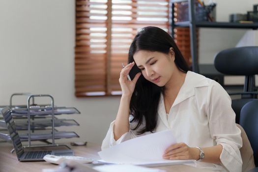 Young business woman working in office suffering from headache