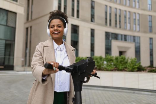 a young American woman marketer with a wide smile stands on an electric scooter in headphones near a business center