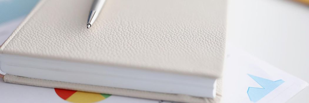 Closed beige leather diary with silver pen, new notebook for notes