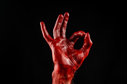 Male hand stained with blood on a black background. Gesture ok.