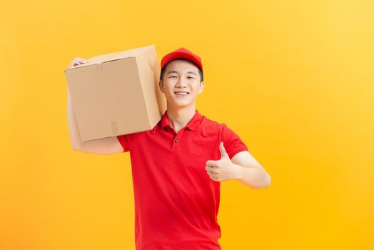 Delivery man with box showing thumb-up on color background